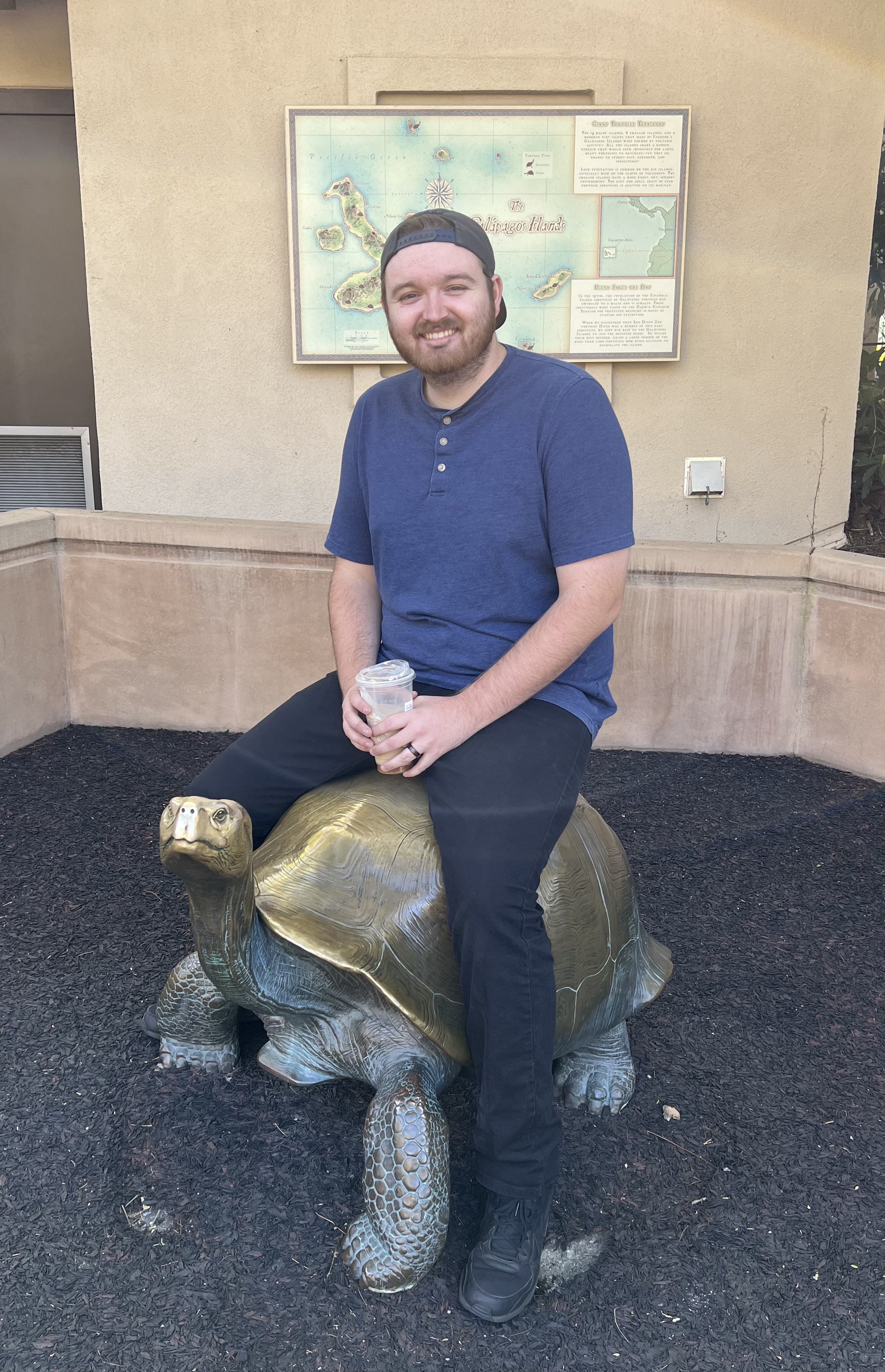 a picture of Ryan Wehr sitting on a turtle statue.